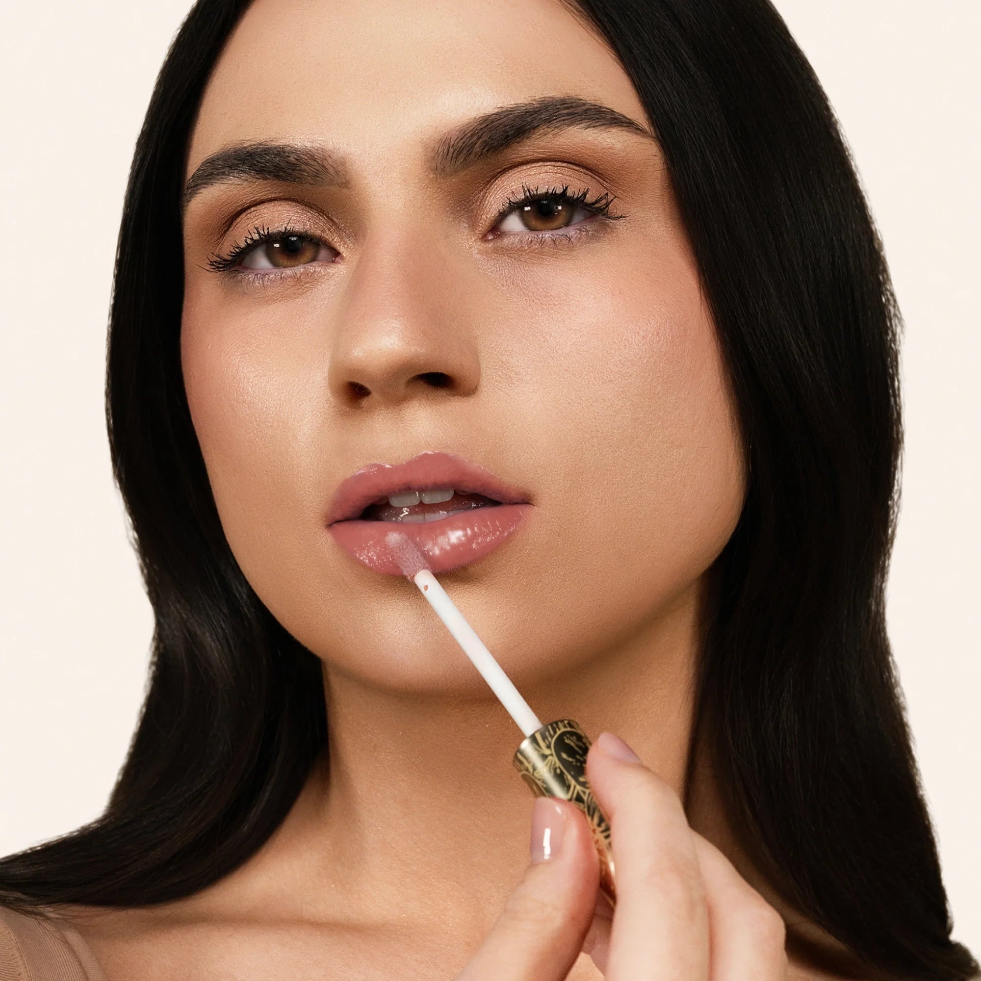 Model applying Glowify Juicy Plumping Lip Gloss product shade Beachy Gleam.