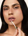 Model applying Glowify Juicy Plumping Lip Gloss product shade Beachy Gleam.