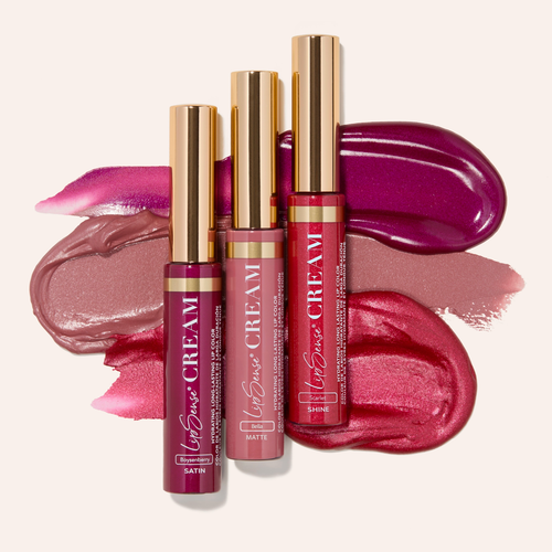 Assorted lip gloss tubes with gold caps over pink and purple lipstick swatches