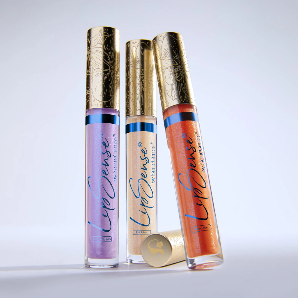 Three LipSense Prismatic gloss tubes with ornate gold caps standing upright.